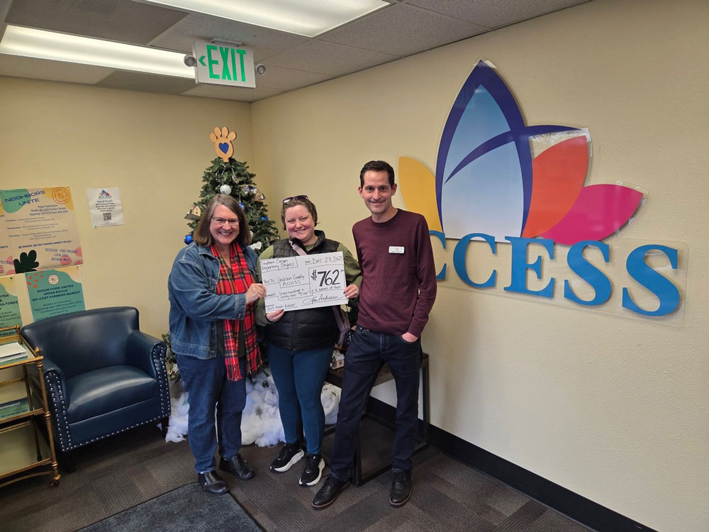 Southern Oregon Repertory Singers' Members holding a check showing a donation to Access Jackson County