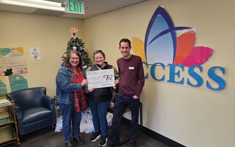 Southern Oregon Repertory Singers' Members holding a check showing a donation to Access Jackson County